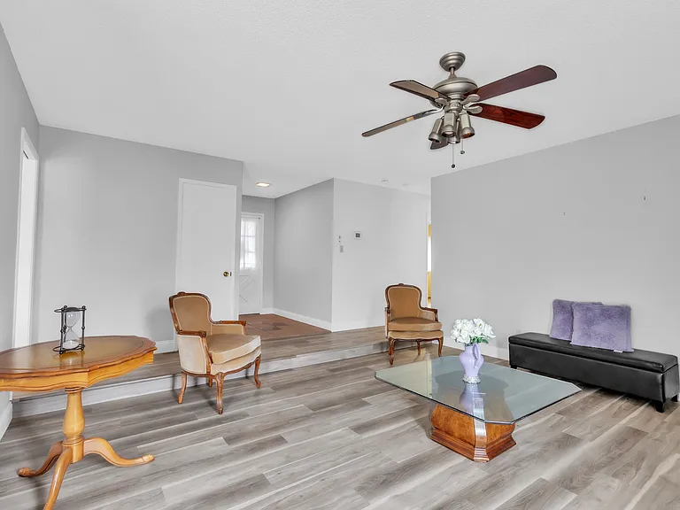 Sitting/reading room. two sitting chairs a bench. one end table and one coffee table. Ceiling fan with light. Fireplace too. wooden floors.