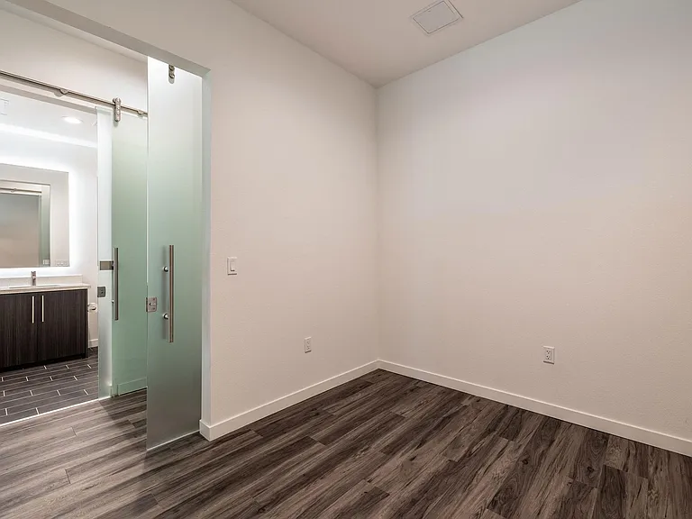 Spacious bedroom with hardwood flooring and high ceilings in a Live and Work apartment at 1400 FIG Apartments in Los Angeles, California.