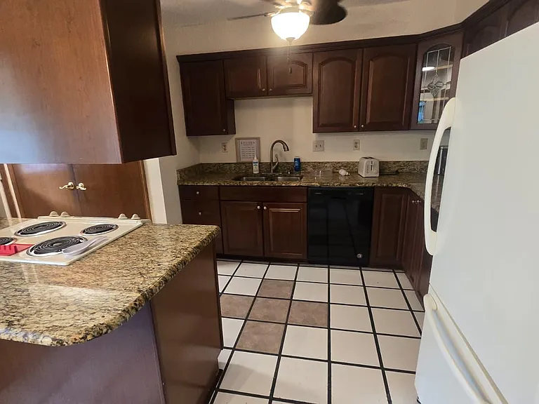 Kitchen with ample wood cabinetry, granite-look counters, breakfast bar, and full appliance set for everyday cooking.