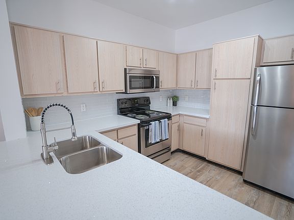Kitchen w/ stainless steel appliances, quartz counters, and tile backsplash