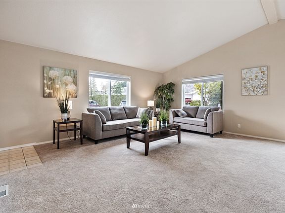 Living Room with vaulted ceilings and an abundance of natural light. New carpet throughout! 
