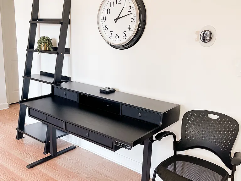 Comfortable bedroom with dedicated workspace and shelving for remote work or study.