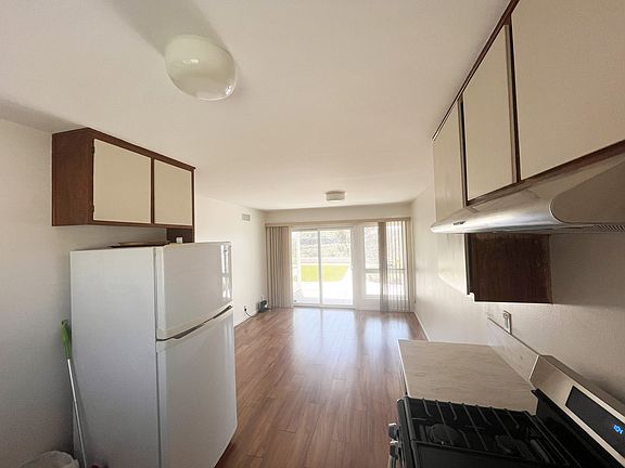 Kitchen refrigerator, open dining area leading to backyard patio sliding doors.