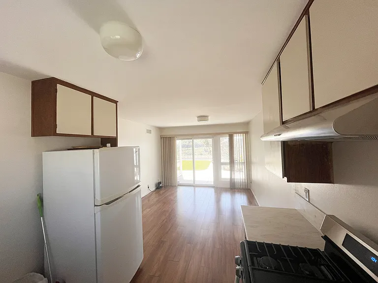 Kitchen refrigerator, open dining area leading to backyard patio sliding doors.