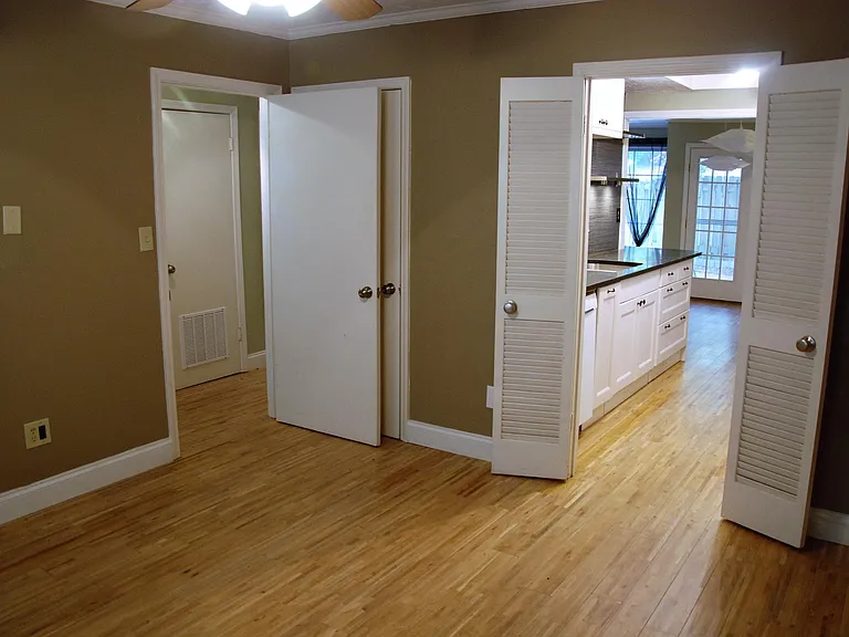 View from corder of main-level flex room off kitchen; currently has louvered door, closet, and window.
