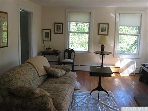 Light filled livingroom with wood floors, cast iron baseboard heat & wood stove.