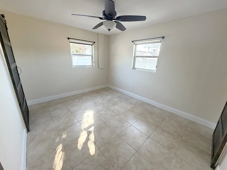 The master bedroom offers abundant natural light, a ceiling fan for comfort, and modern barn doors. (Angle 4)