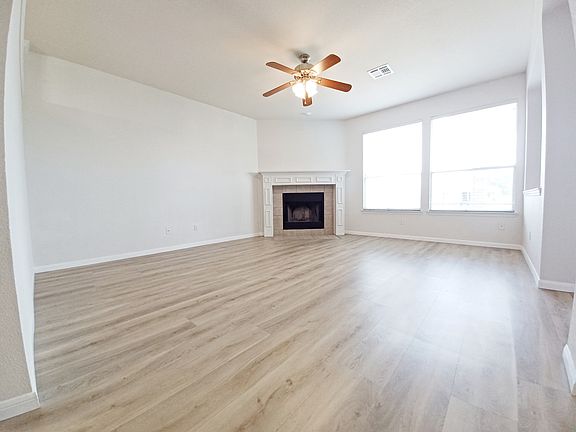 Second spacious living area with fireplace, new LVP flooring, large windows, and open flow to kitchen and dining.