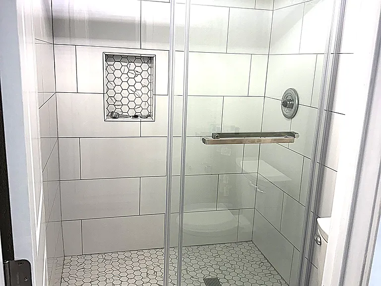 Primary shower with barn door enclosure doors and niche for soap and shapoo.
