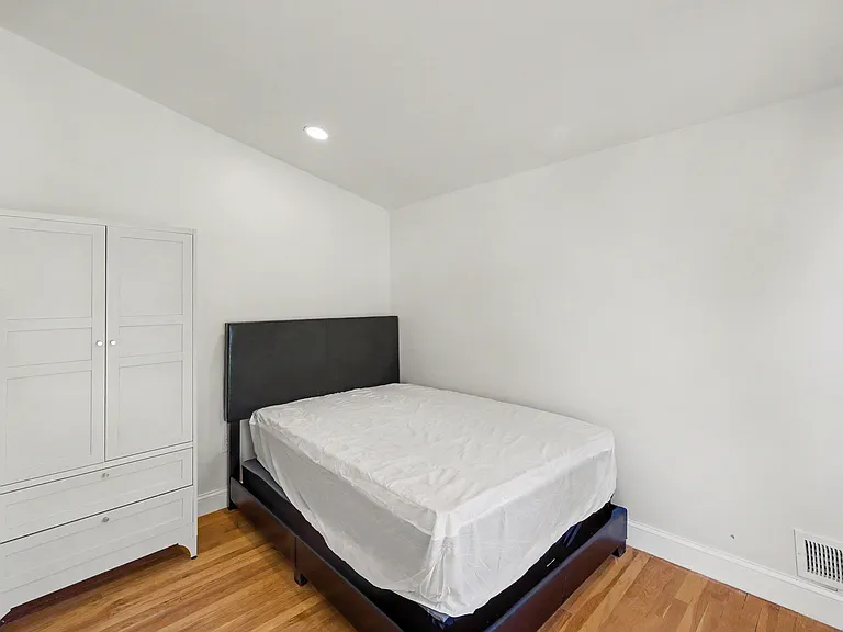 Furnished bedroom with hardwood floors, a bed frame, and wardrobe storage for convenient everyday living.