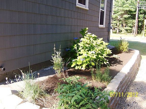 stone wall along home with garden