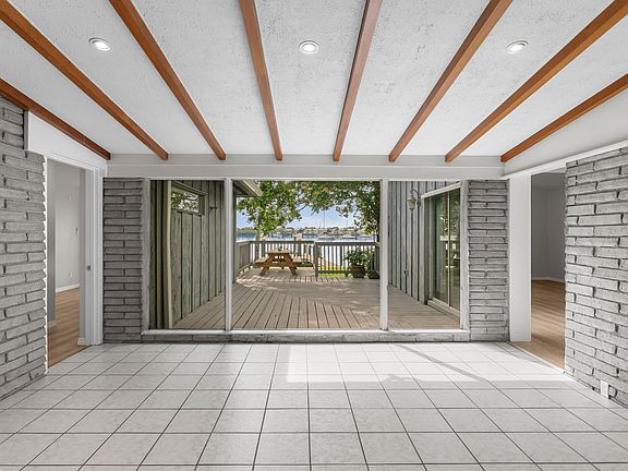 Framed by wood-beamed ceilings and brick walls, the dining space evokes classic Florida charm, with views across the secluded courtyard deck and shimmering bay beyond.