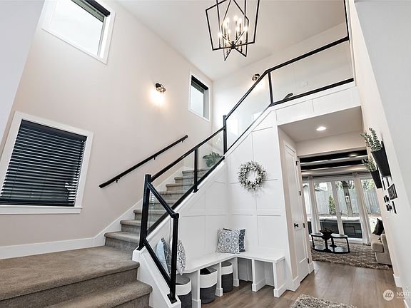 The soaring 2 level foyer offers a built-in bench and modern metal & tempered glass railing. The blinds were made to order and the upper level blinds are motorized for easy use>