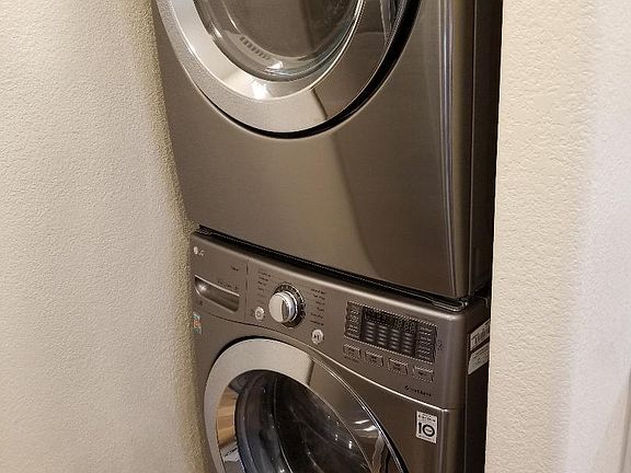 Full size stacking washer and dryer are located in a nook in the kitchen.