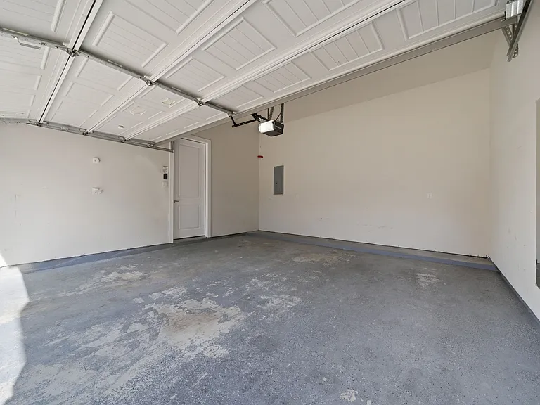 Spacious garage featuring a concrete floor, white walls, and an automatic garage door opener. Offering excellent versatility, this space is ideal for secure parking and additional storage.