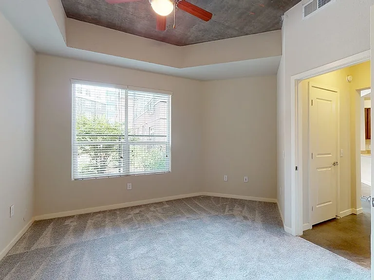 Spacious apartment bedroom with large closet and plush carpet flooring.