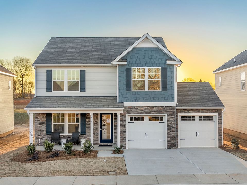 A large blue and white house with two garages and a porch.