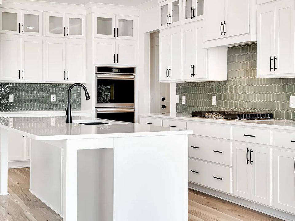 Exquisite white cabinetry and chic green backsplash define this Northridge Park kitchen s elegance a