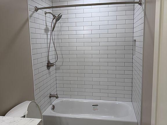 Guest bath includes Tub, Custom Tile with Shampoo Niche, and Curved Shower Curtain Rod