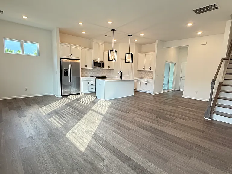Open-concept layout featuring a gourmet kitchen, spacious living area, and elegant staircase.