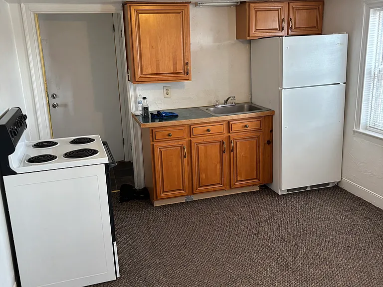 Bright kitchen wit medium oak cabinets, stove and fridge.