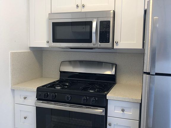 Brand new kitchen with quartz counter tops, white shaker cabinets, and stainless steel appliance.