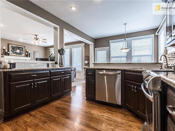 Eat in kitchen with newer stainless appliances,beautifully refinished hardwood floors and dark cabinets.