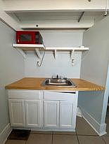 Kitchen Area Near AC Unit View of Sink, Microwave and Storage Area