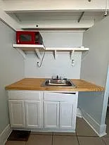 Kitchen Area Near AC Unit View of Sink, Microwave and Storage Area