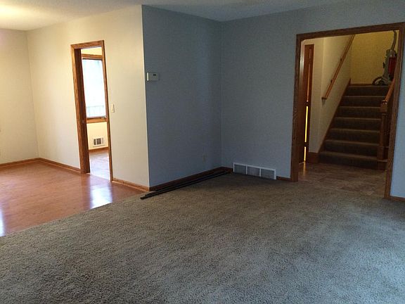 Main level - unfurnished view. The hardwood is the dining room, the carpet is the living room and you can see it opens to the stairway leading to the bedrooms. At the base of the stairs is the half bath.