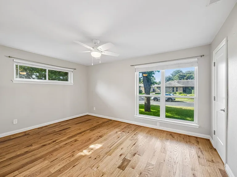 Spacious room featuring wood-finish flooring, light gray walls, and white trim