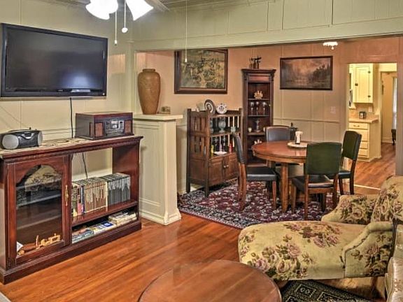 Living room and dining room with hardwood floors and ceiling fans. Kitchen and back room in distance.