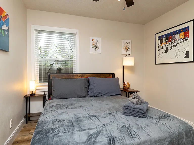 Cozy bedroom with a plush queen bed, soft lighting, modern art, and a dedicated workspace. Peaceful and stylish_perfect for relaxing or getting work done.