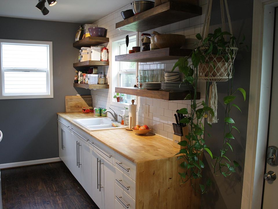 Renovated kitchen includes custom cabinets and butcher block counters, open shelving, and subway tile backsplash.
