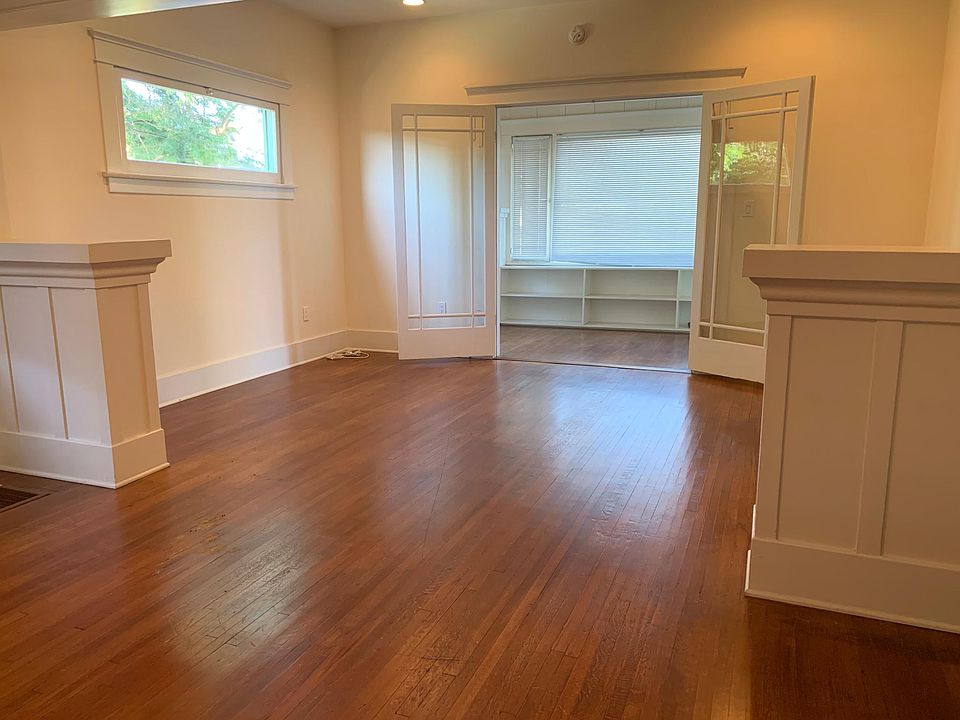 Large Living Room/Dining Room. Hardwood floors. Built-in bookshelves and room dividers. Bonus Room with glass French doors and view window make a great home office. Morning light.