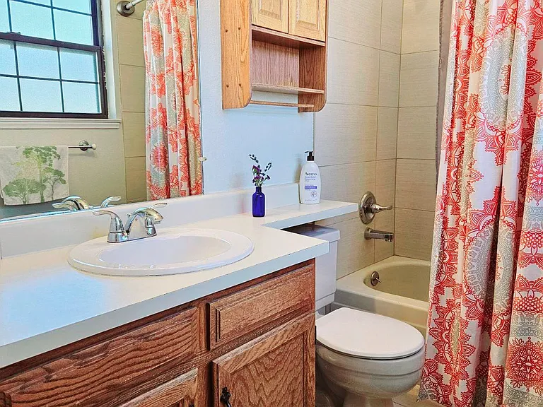 Newly tiled bathroom with updated sink and lighting. Just outside the door is a full size linen closet for lots of storage.