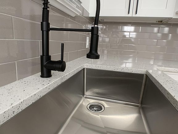 Large, stainless sink with a matt black telescoping faucet