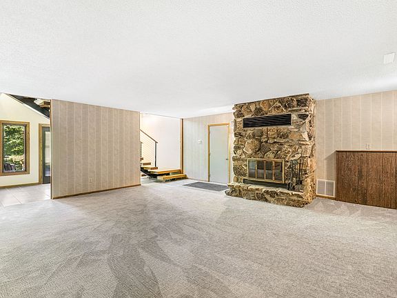 indoors you'll find a family room, and can see the wood burning fireplace, stairway up, and door to the heated garage.