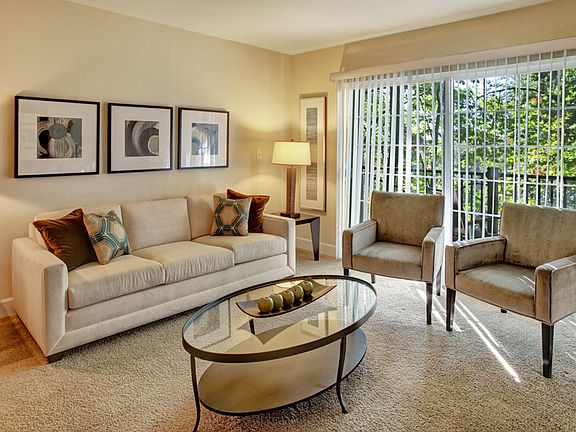 Living room with couch, table, and entertainment center with large sliding glass doors leading out to the balcony