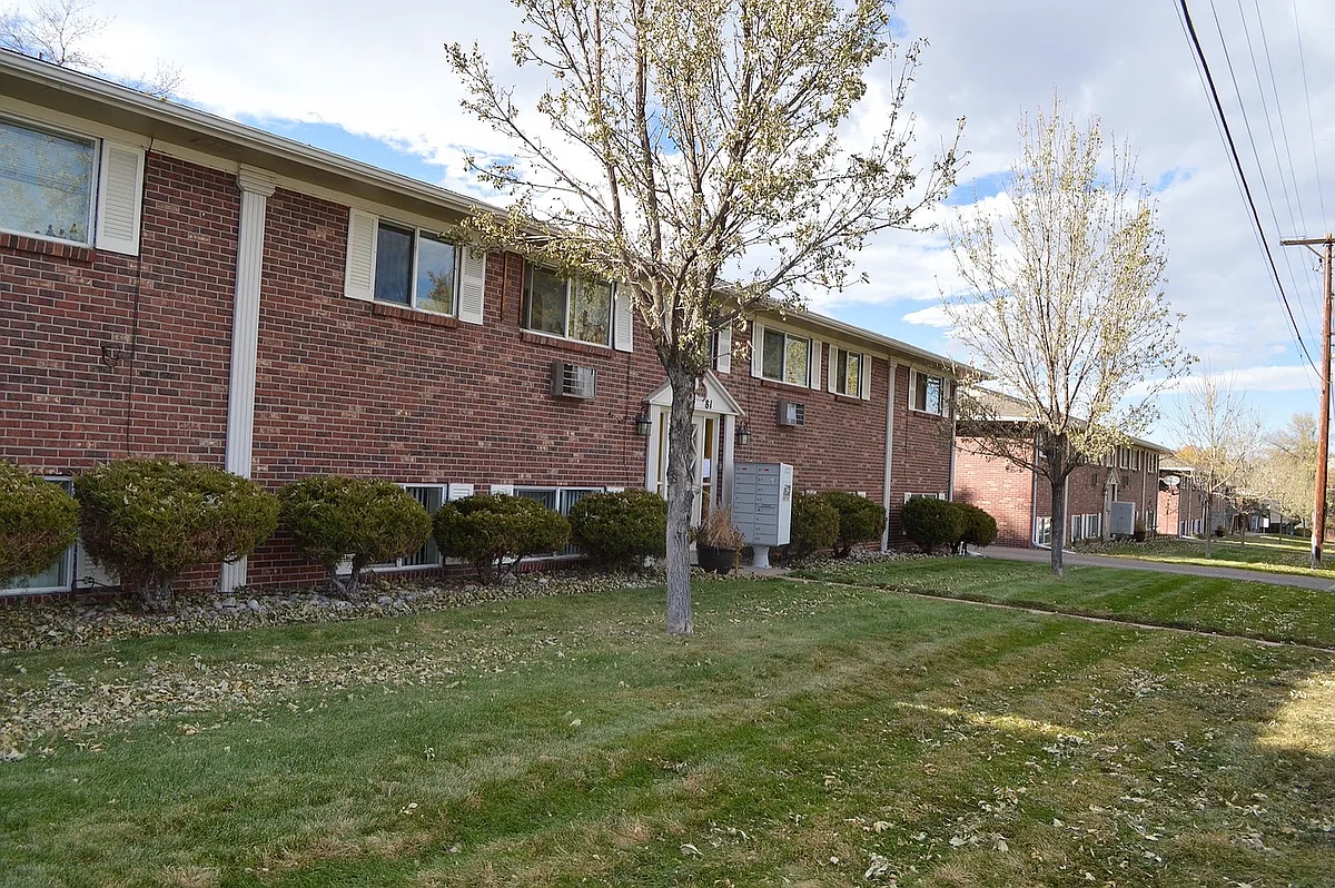 Welcoming brick apartment complex with lush green landscaping, mature trees, and a serene neighborhood setting. - 5351 S Delaware St