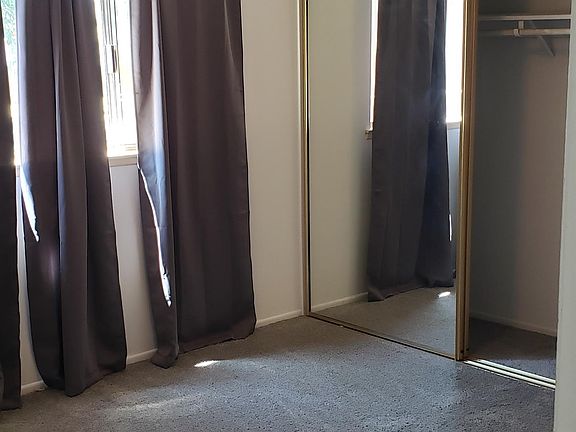 Bedroom with mirror closet doors and new carpet.