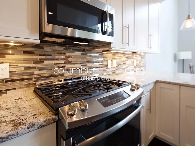 kitchen detail: white granite tops, glass tile backsplash, under-cabinet lighting, high-end appliances