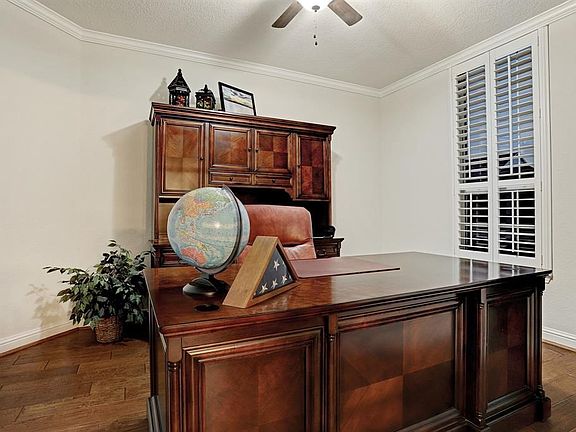 Formal office with plantation shutters, hardwood flooring and ceiling fan.