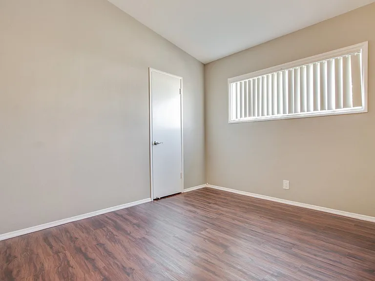 Bedroom with walk-in closet, vertical blinds, wood-inspired flooring