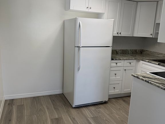 Eat-in kitchen area with full-size refrigerator. There is a window to the left.