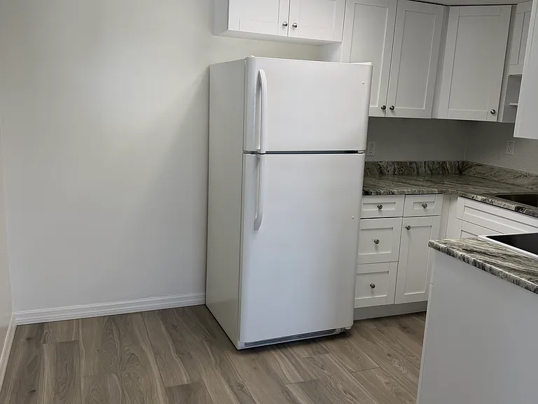 Eat-in kitchen area with full-size refrigerator. There is a window to the left.