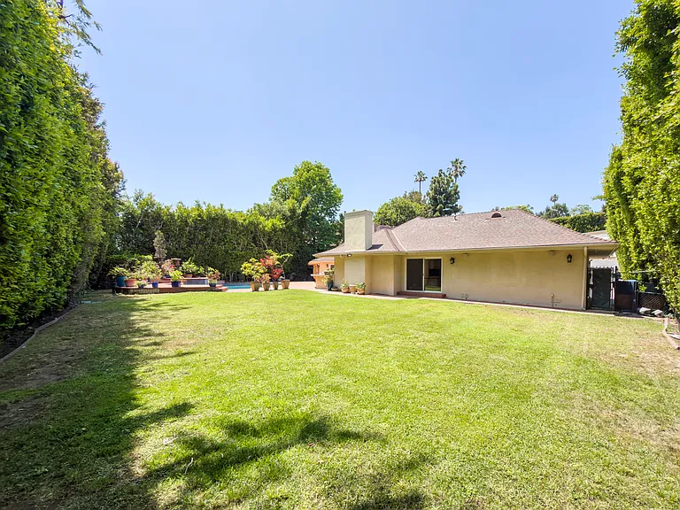 Sprawling backyard lawn framed by tall hedges offers room to play at this Beverly Hills luxury rental, 1094 Garden Lane, 90210.