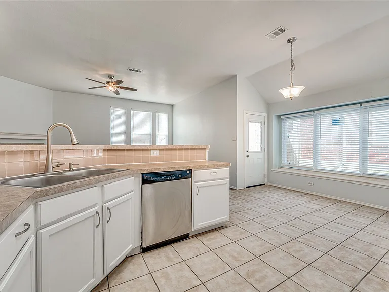 Kitchen featuring a stainless steel double basin sink, brushed nickel faucet, and white cabinetry