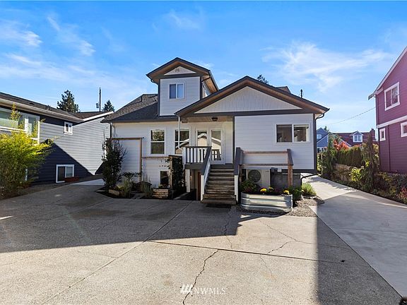 Back of the house with ample driveway space leads to detached garage and partially fenced grass play area