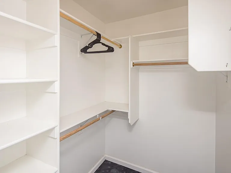 Spacious walk-in closet with built-in shelving and dual hanging rods for organized storage.